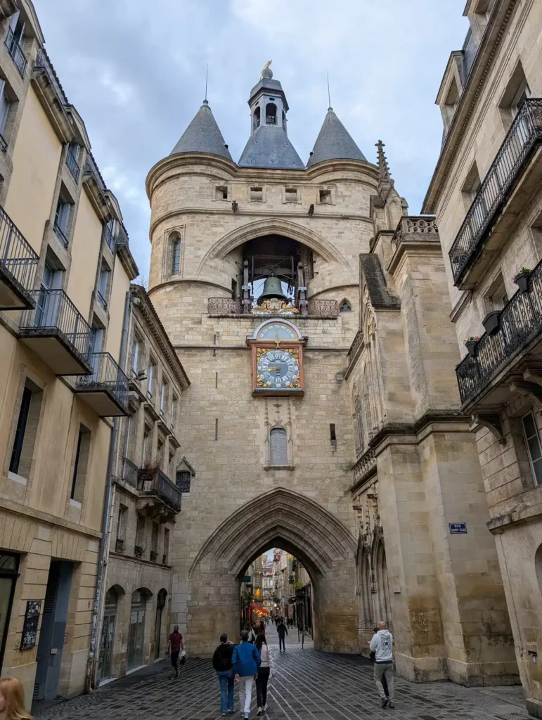A tall, medieval city gate, with turrets and a bell.