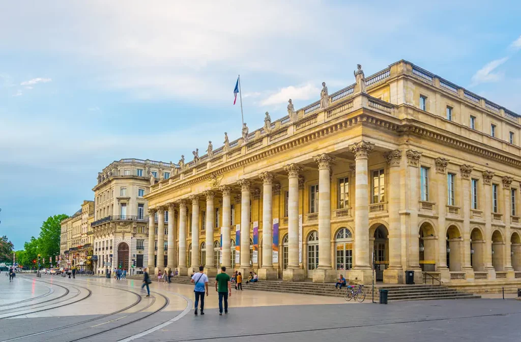 A grand, Classical style building in golden stone with lots of columns