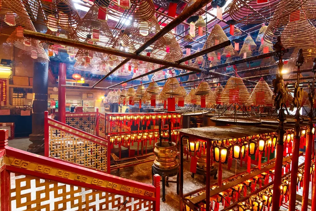 Inside Man Mo Temple in Hong Kong. There are coils of incense hanging from the ceiling and red accents everywhere.