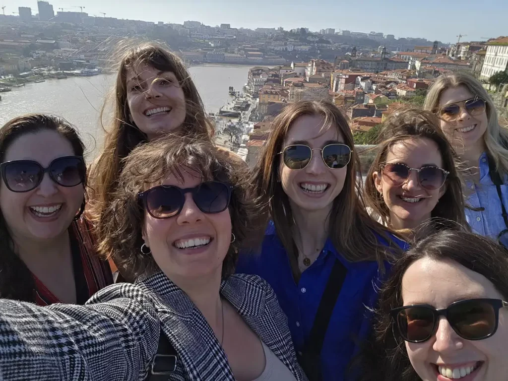 A group of women in sunglasses in front of the Porto skyline