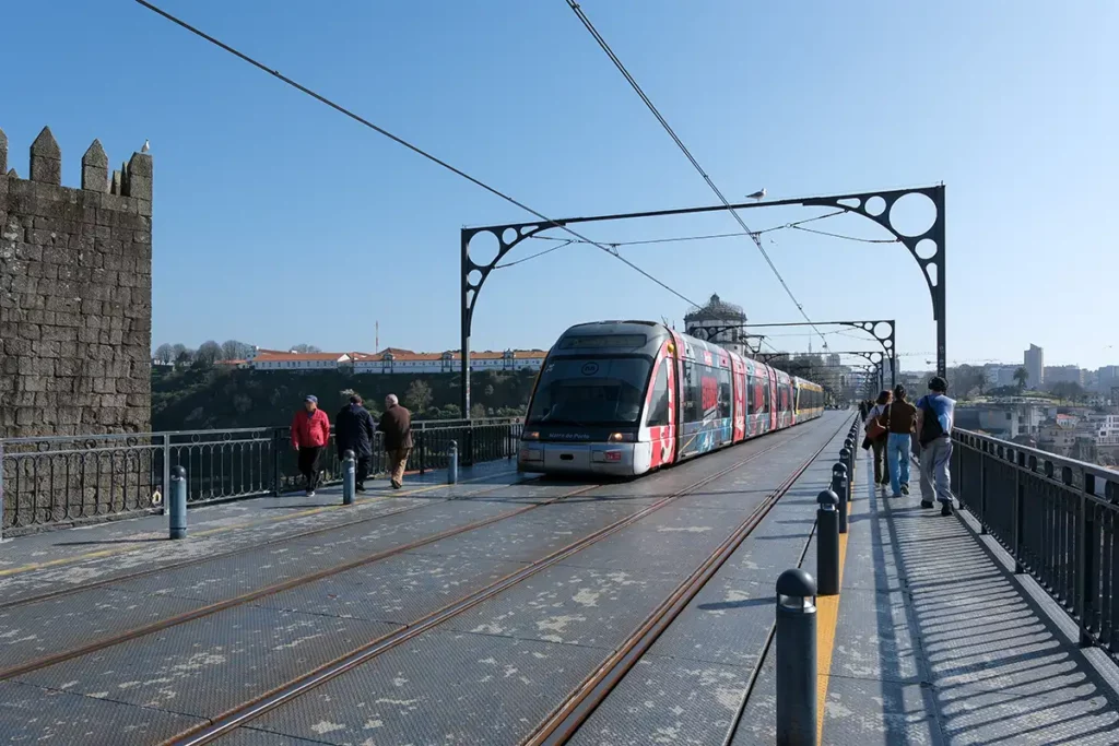 A modern tram crossing the top deck of the Dom Luís I Bridge in Porto