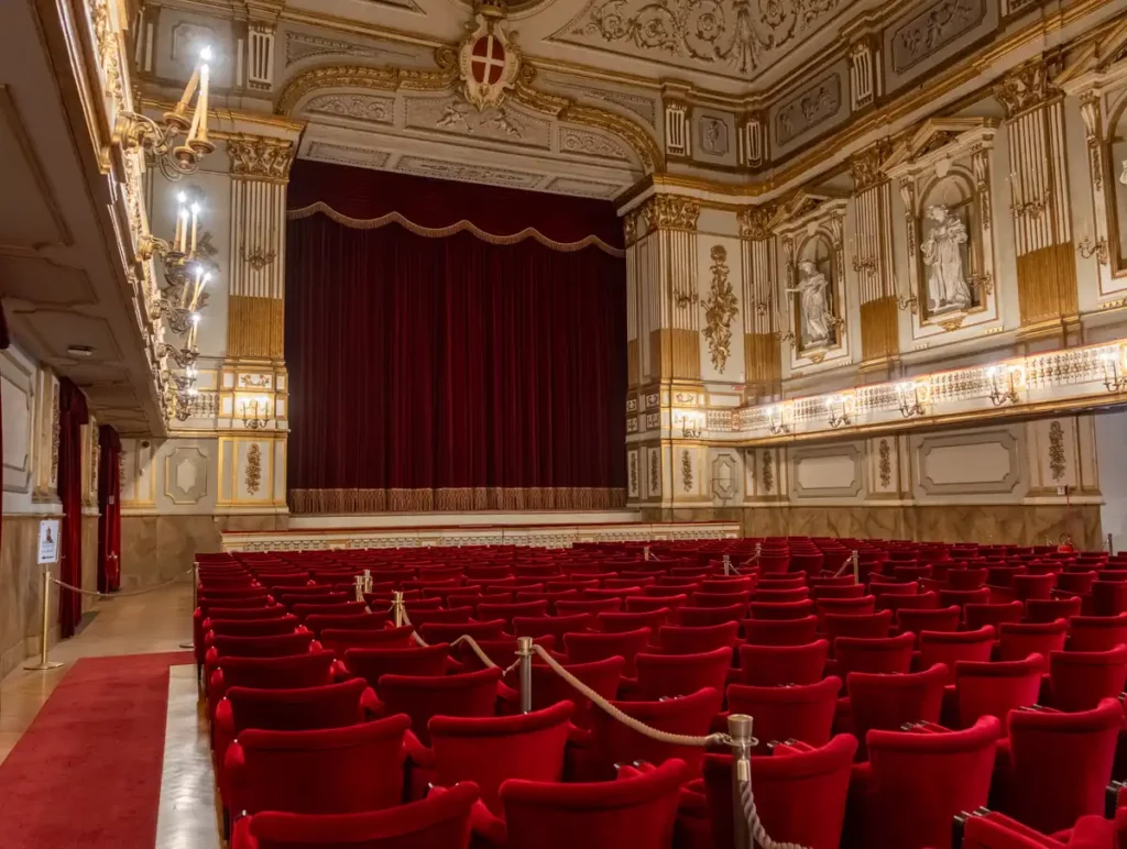 A theatre with red velvet seats and ornate wall decoration