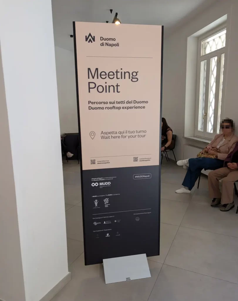 A sign inside a building showing where to meet for the rooftop tour